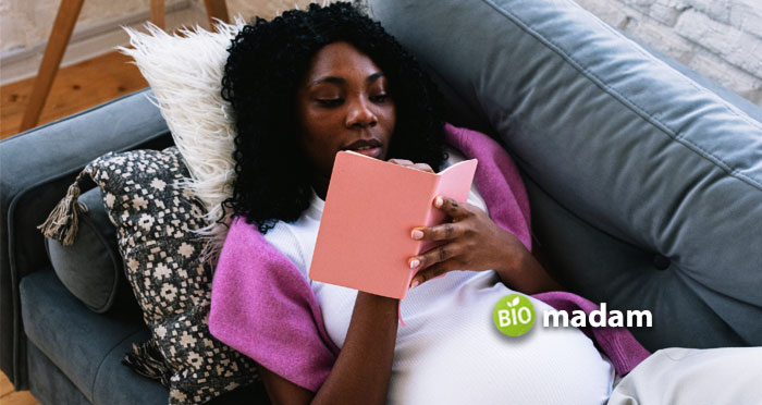 black-pregnant-woman-writing-in-notebook-on-couch